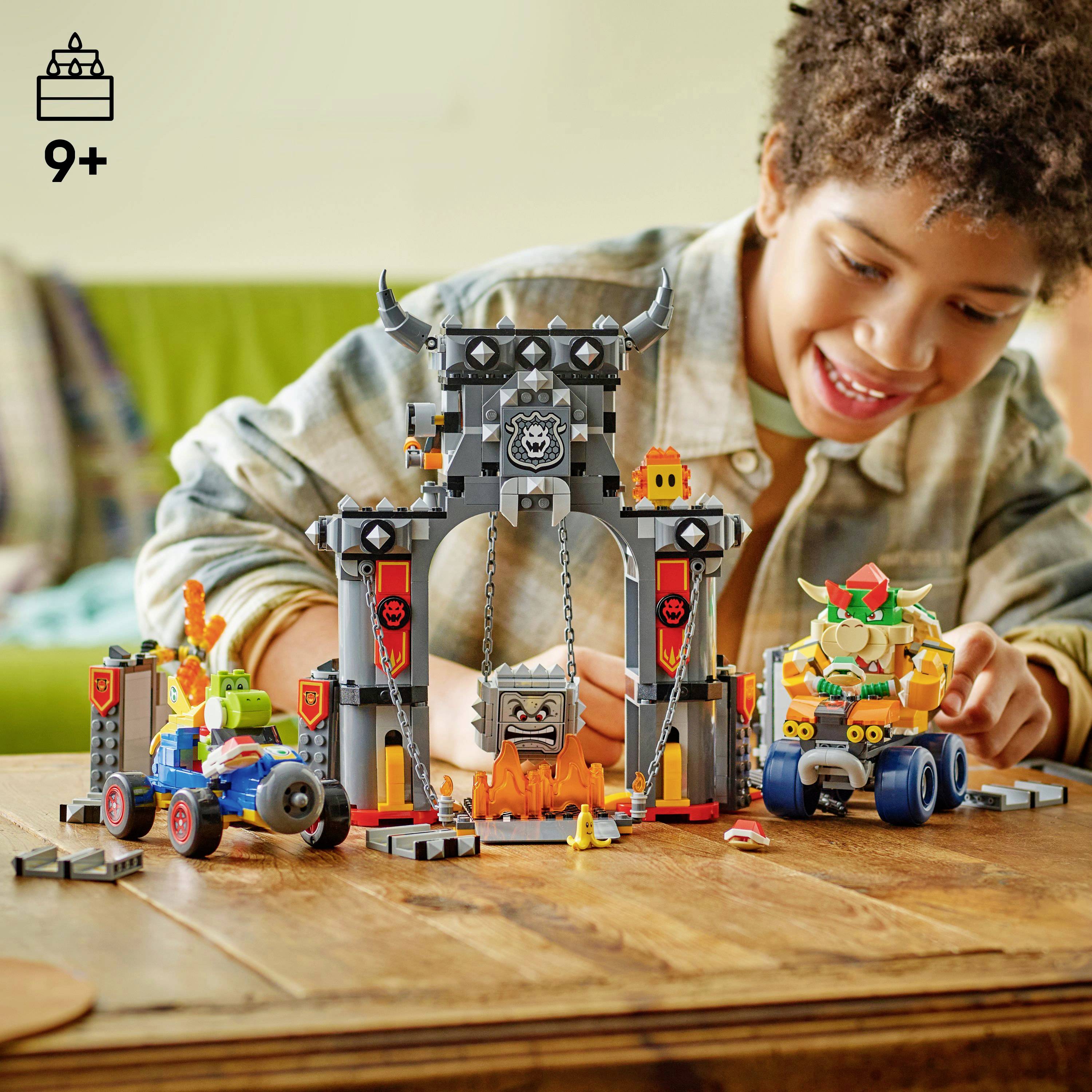 Un enfant assemble joyeusement un ensemble LEGO sur le thème des châteaux, avec divers personnages et véhicules colorés. L'ensemble est étiqueté pour les 9 ans et plus.