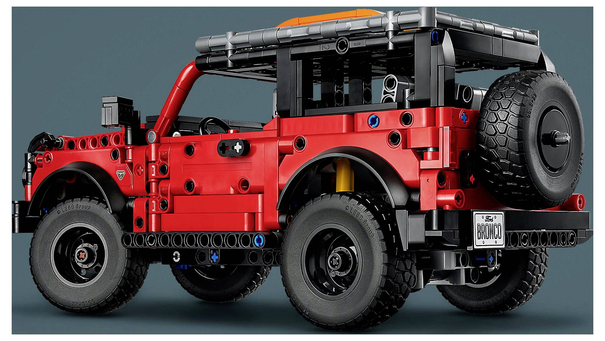Un modèle de bloc de construction rouge et noir d'un véhicule tout-terrain avec de grandes roues et une roue de secours à l'arrière, étiqueté « BRONCO ».