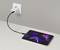 Une tablette en charge sur un plan de travail, connectée à une prise murale via un câble et un chargeur USB-C. La tablette affiche un design abstrait et vibrant.