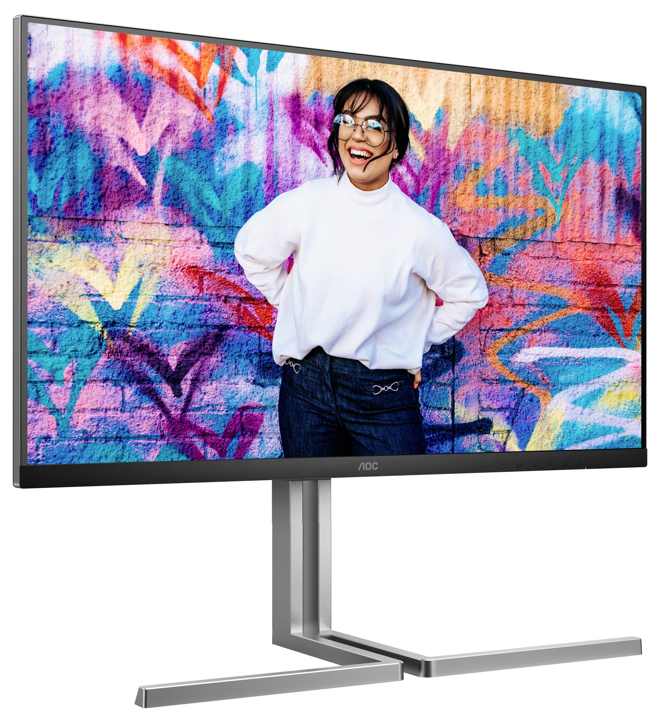 Une personne joyeuse portant des lunettes et un pull blanc se tient devant un mur coloré peint avec des graffitis.