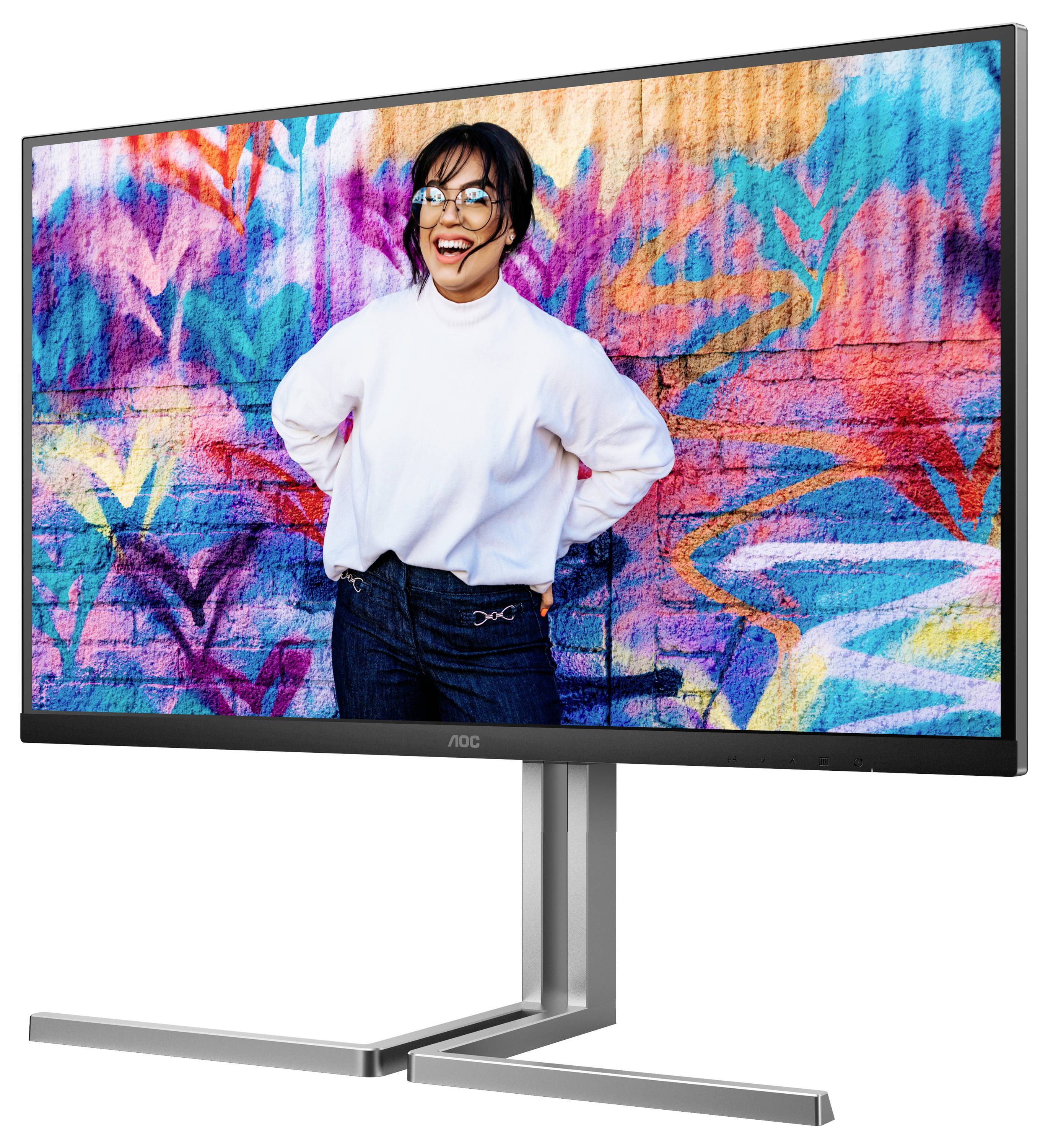 Une personne sourit devant un mur coloré décoré de graffitis. Elle porte des lunettes et un pull blanc.