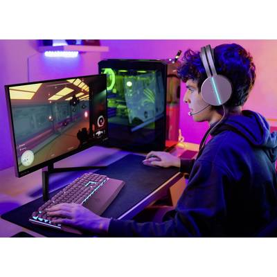 Un jeune homme est assis à un bureau et joue à un jeu vidéo sur un ordinateur. Il porte un casque et utilise un clavier et une souris.