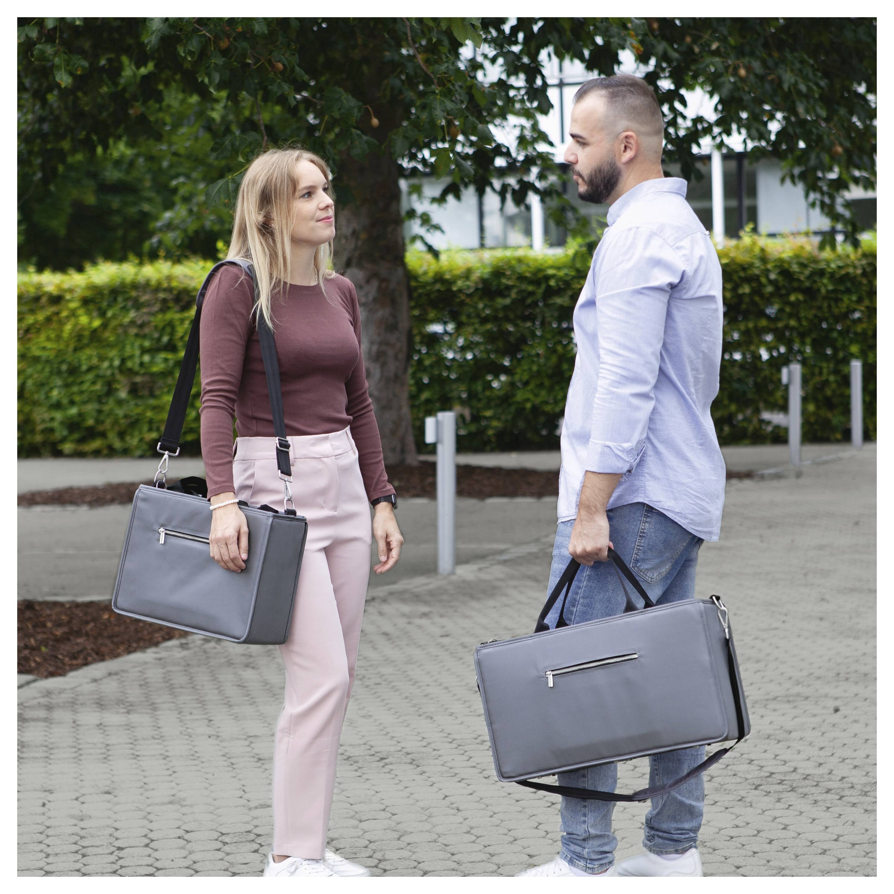 Un homme et une femme se tiennent face à face en plein air, chacun tenant une mallette grise, comme s'ils se rencontraient ou discutaient sur un trottoir.