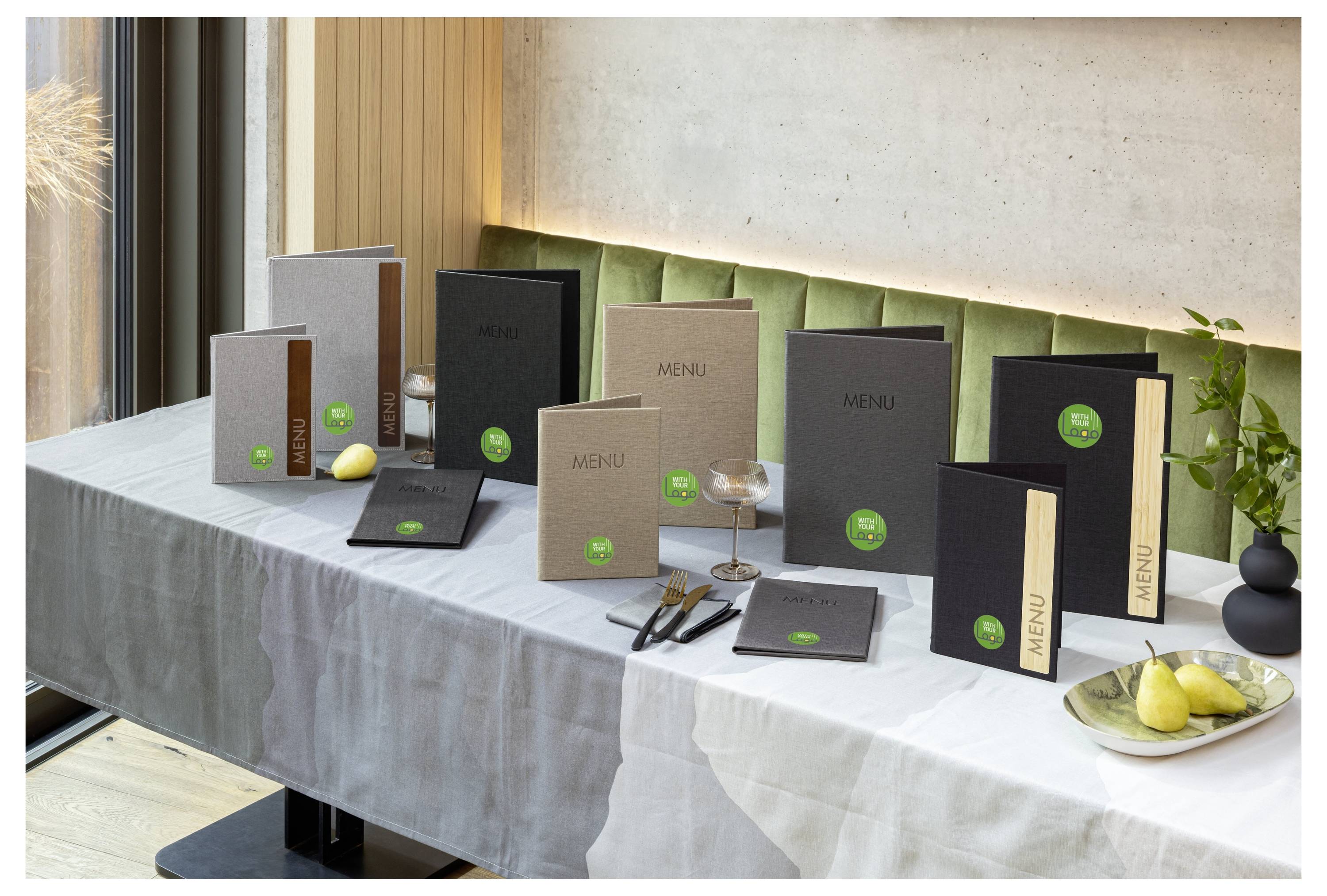 Une table affiche des livrets de menu assortis et des cartes de différentes tailles et couleurs, avec quelques poires et des verres, suggérant une présentation de menu de restaurant.