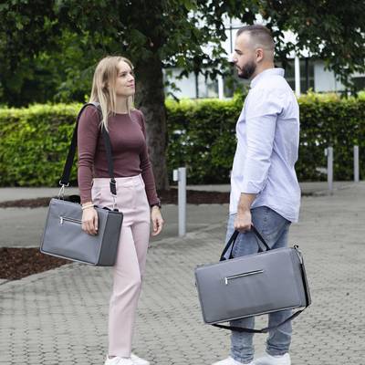 Un homme et une femme avec des serviettes se font face sur un chemin pavé et discutent.