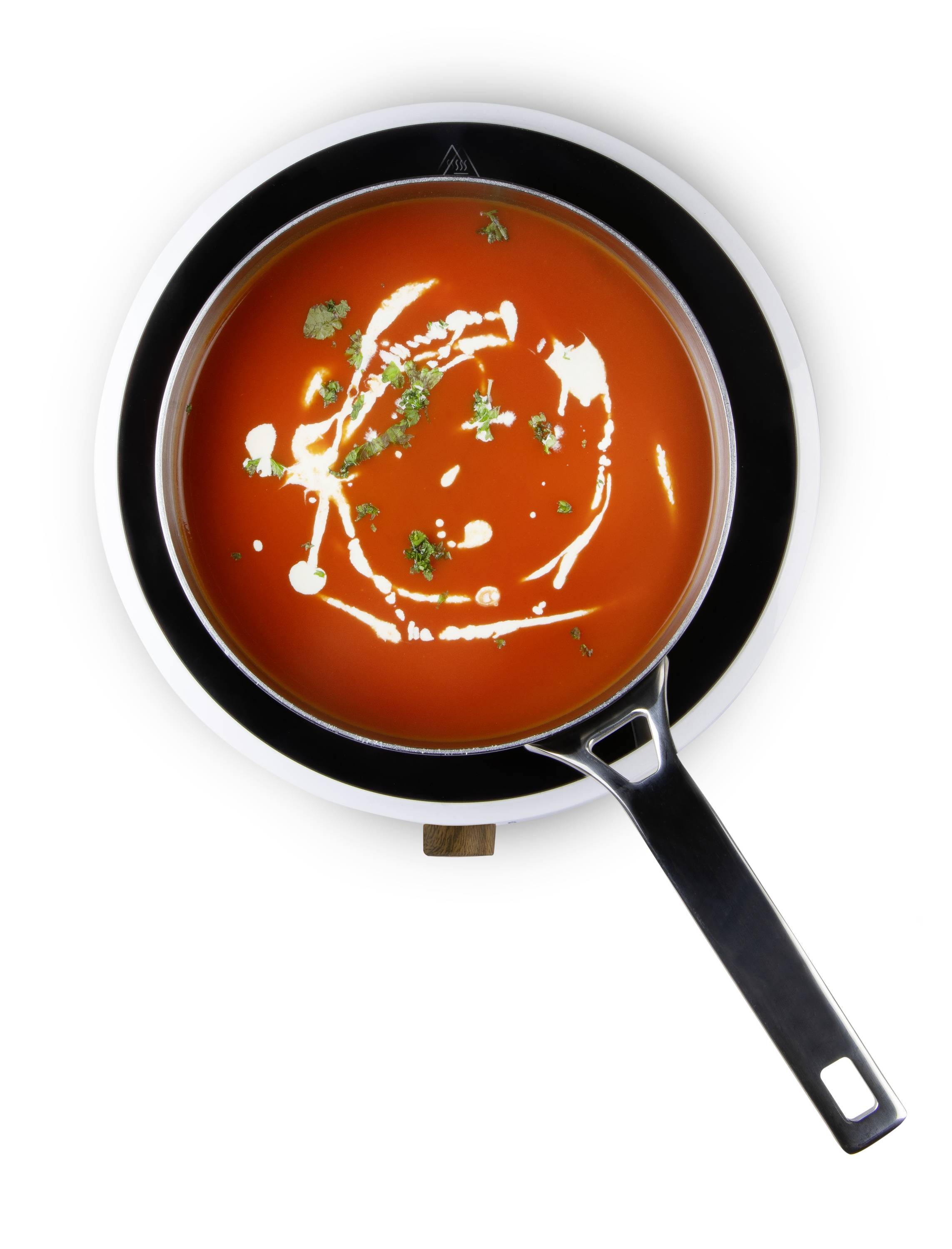 Un bol de soupe aux tomates, garni d'un filet de crème et d'herbes, vu de dessus.