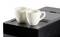 Deux tasses blanches sont posées sur une machine à café automatique noire. Les tasses sont vides et prêtes à être remplies de café.