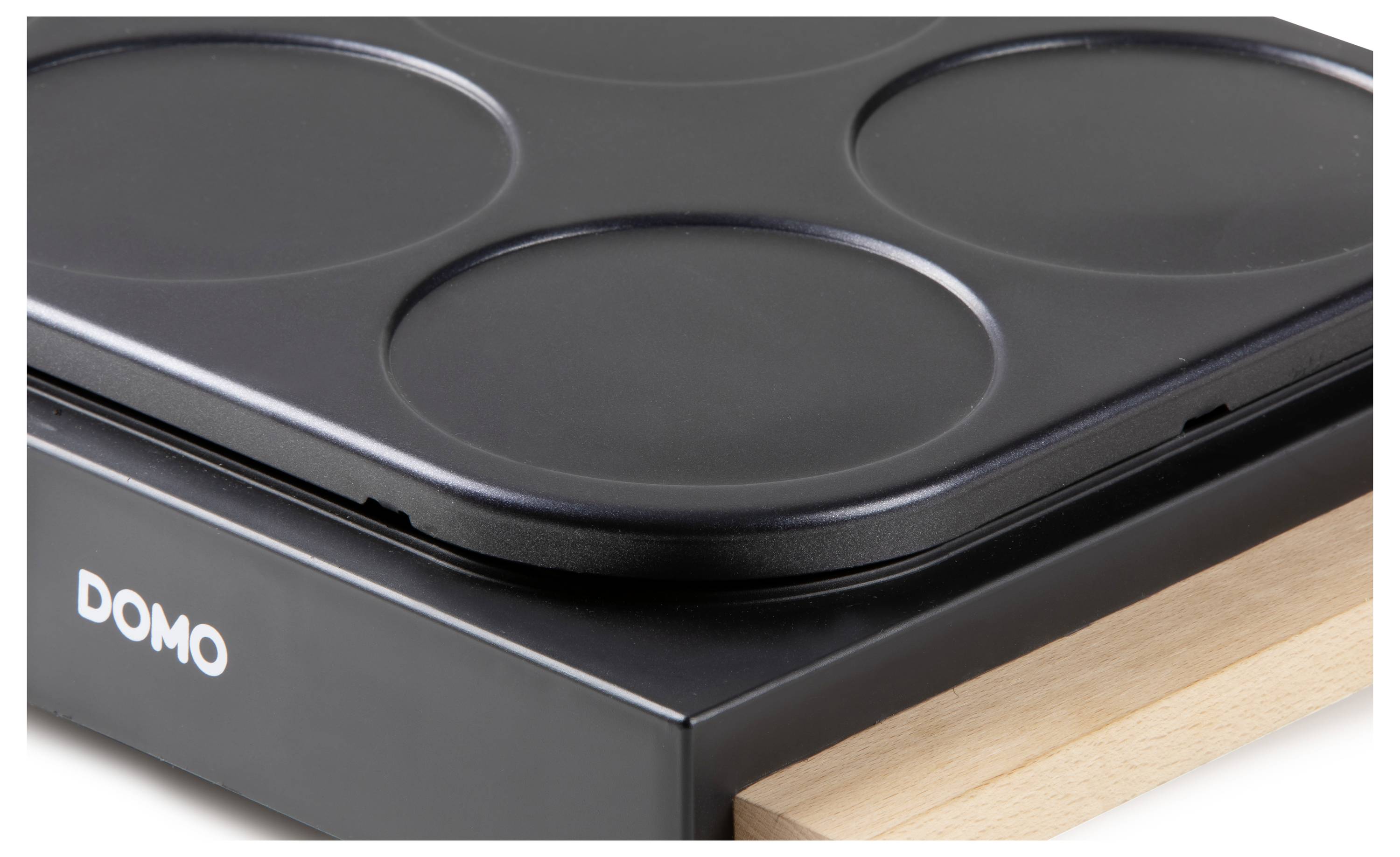 Plaque de crêpes noire avec quatre cavités rondes, logo de marque 'DOMO' sur la face avant ; adaptée pour une cuisson simultanée.