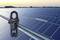 Un multimètre mesure la tension sur des modules solaires au coucher du soleil. L'affichage principal indique 1500, ce qui suggère un test d'électricité. Les énergies renouvelables sont au centre de l'attention.