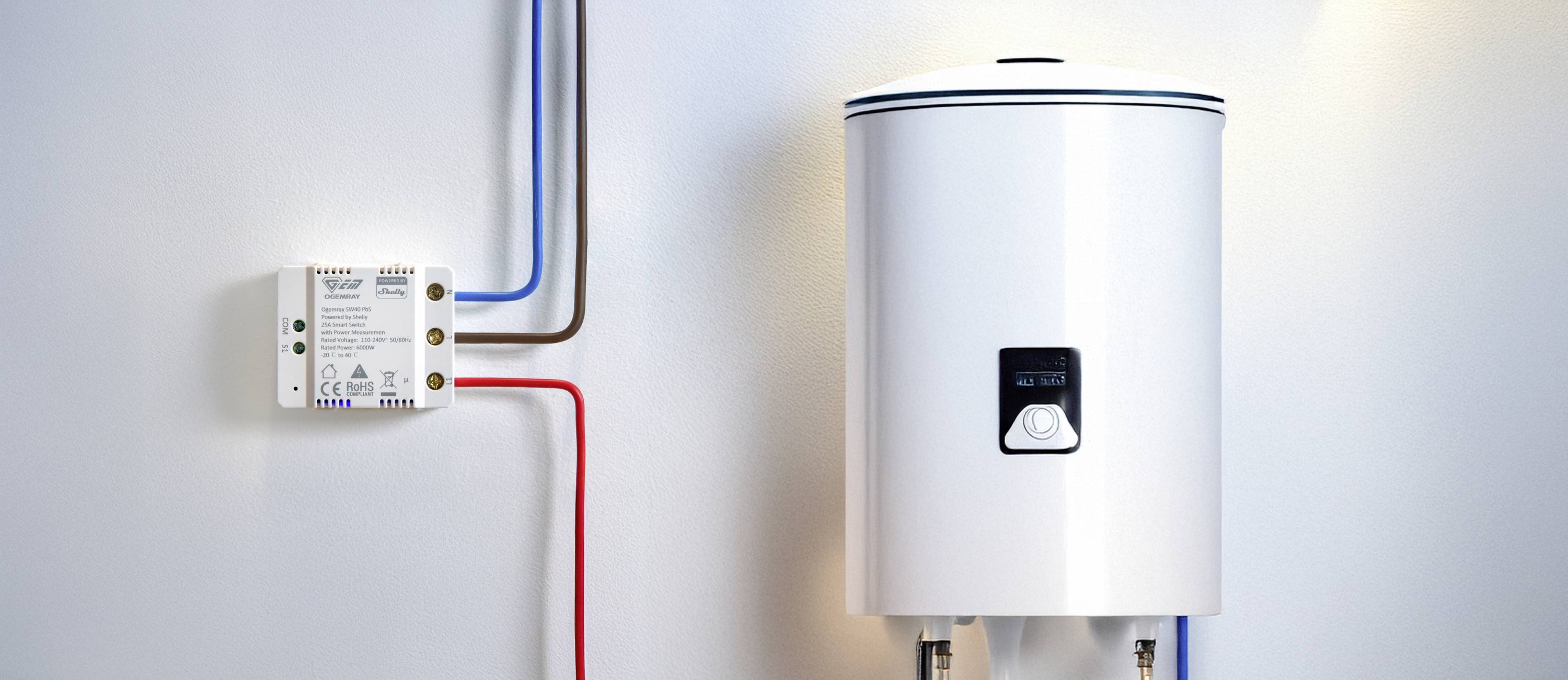 Chauffe-eau électrique monté au mur, relié à des tuyaux colorés et à un boîtier de commande. Installation de système de chauffage.