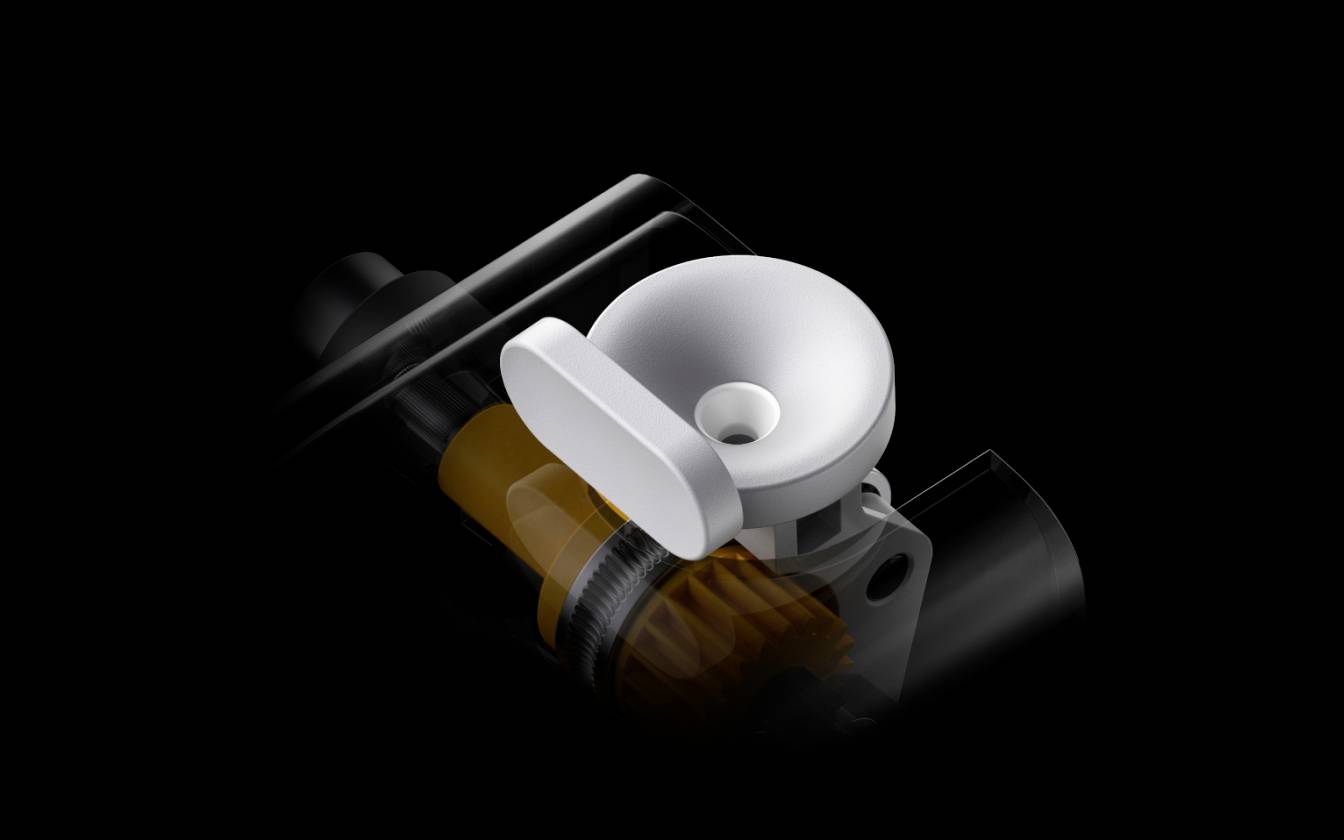 Un appareil noir avec un bouton rond blanc au centre. Des pièces mécaniques sont visibles en arrière-plan.
