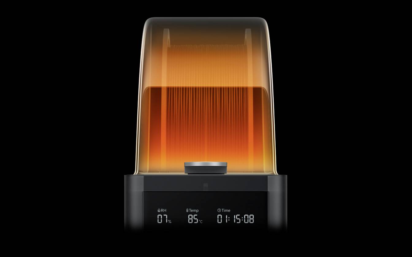 Imprimante 3D avec un couvercle transparent orange affichant une progression de 85% et un temps restant de 1:15:08 sur l'écran.