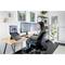 Une femme est assise à un bureau avec trois écrans, travaille sur un ordinateur et porte un casque. La pièce est décorée de manière moderne.