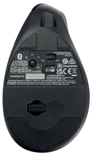 Dessous d'une souris sans fil avec des étiquettes d'identification et de certification, montrant le compartiment des piles et le capteur optique.