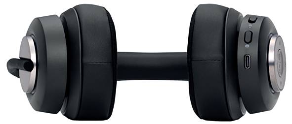 Une paire d'écouteurs over-ear noirs est posée sur une surface blanche. Des touches de contrôle visibles et un port de charge sont présents.