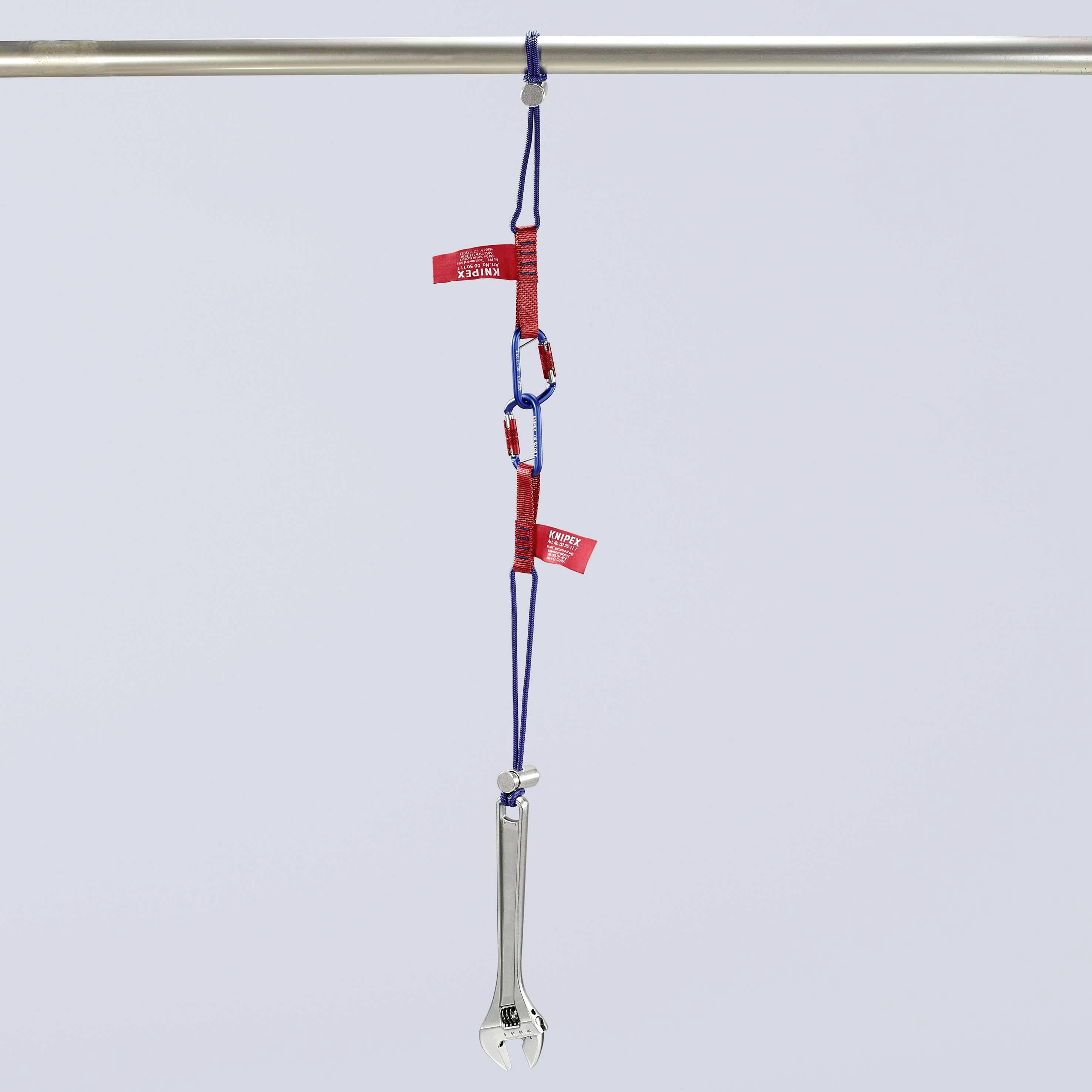 Une clé à molette est suspendue à une barre à l'aide de cordes bleues et de mousquetons. Des étiquettes rouges portant l'inscription 'APPAREIL TESTÉ' sont apposées.