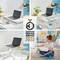 Un ordinateur portable est posé sur un support de laptop réglable en hauteur, placé sur une table. En arrière-plan, une femme est assise par terre et écrit dans un carnet. Le support est récompensé par le label « German Design Award Winner 2022 ».