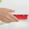 Une main utilise une perforatrice rouge sur une table blanche. La perforatrice poinçonne une feuille de papier.