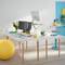 Un espace de travail lumineux et moderne avec des écrans sur un bureau à hauteur réglable. Coussin de siège jaune et accessoires de bureau colorés.
