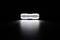 Une barre lumineuse LED rectangulaire illuminée dans l'obscurité, projetant un faisceau lumineux et concentré sur la surface en dessous.