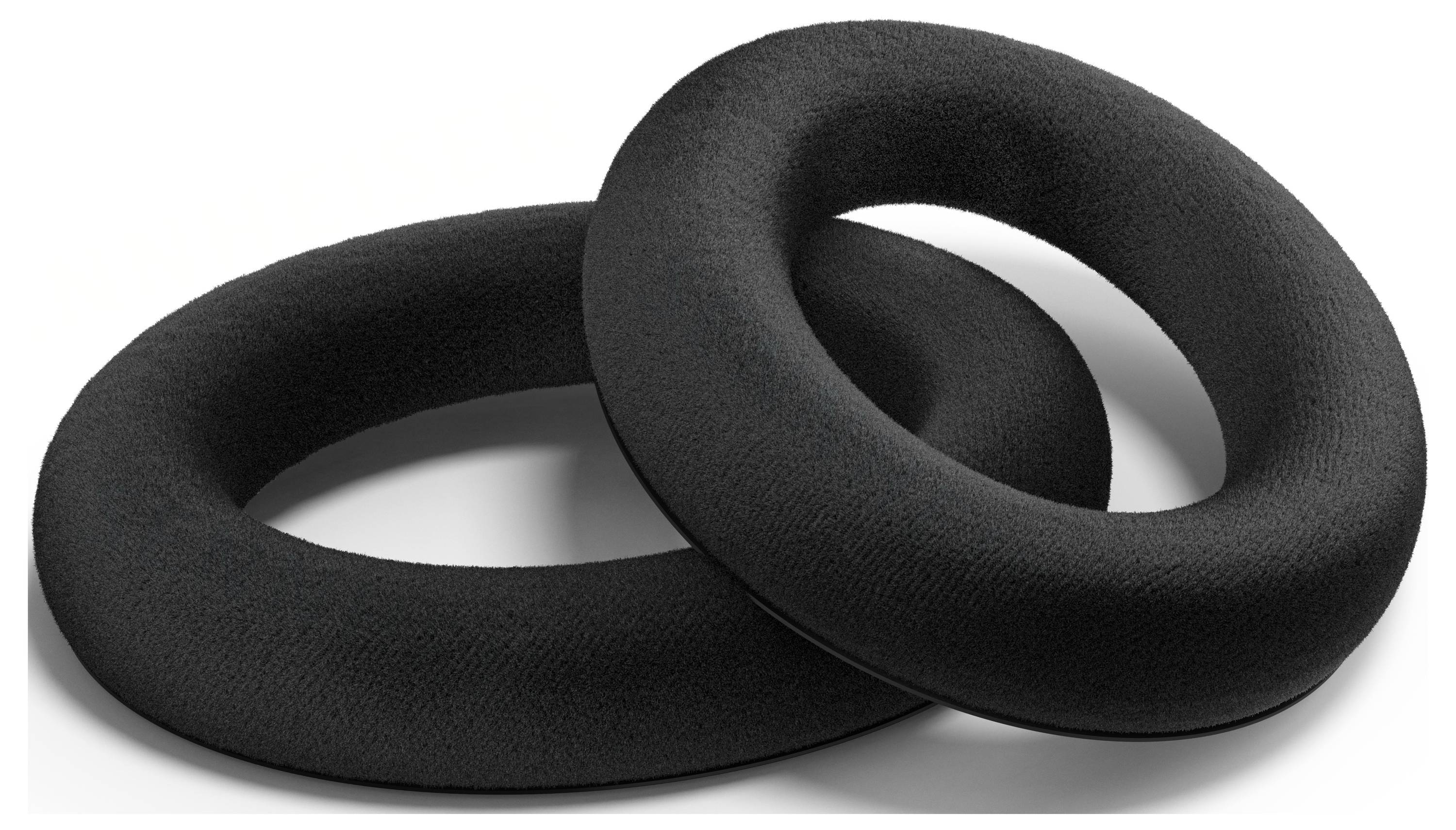 Deux coussinets d'oreilles noirs rembourrés de forme ovale, superposés sur une surface blanche.