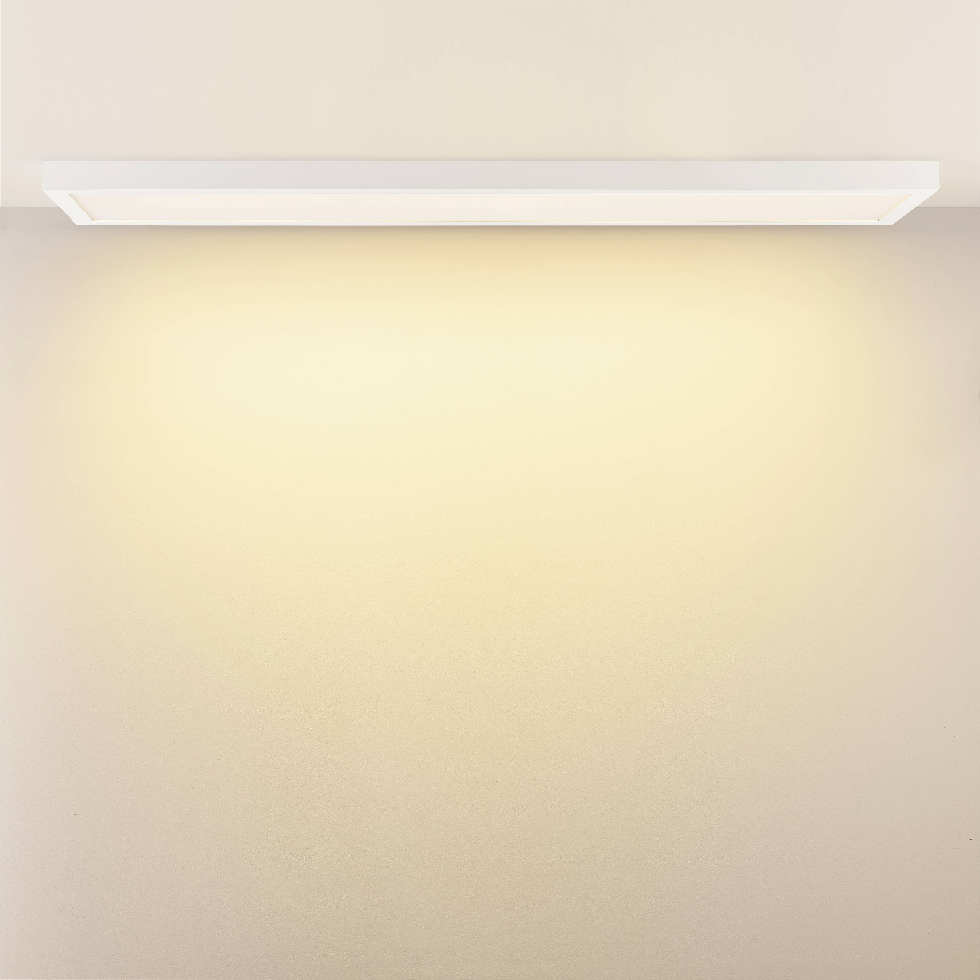 Plafonnier rectangulaire avec une lumière chaude et douce qui diffuse uniformément vers le bas, monté sur un plafond beige clair.