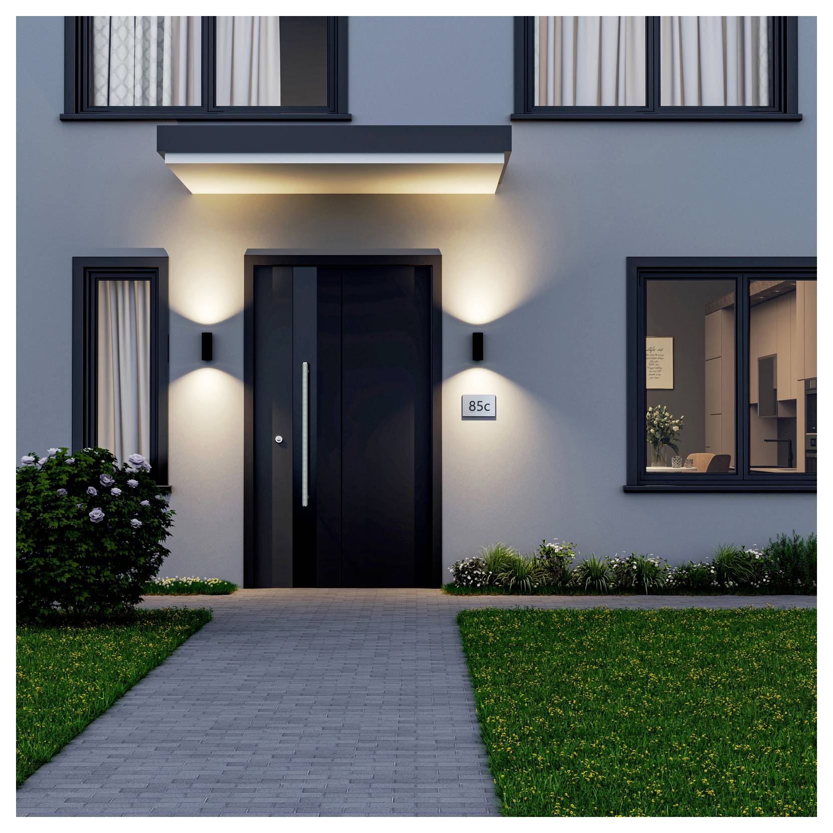 Entrée de maison moderne avec porte d'entrée noire, appliques murales allumées, plaque d'adresse « 85c » et allée menant à travers un jardin paysager à l'avant.