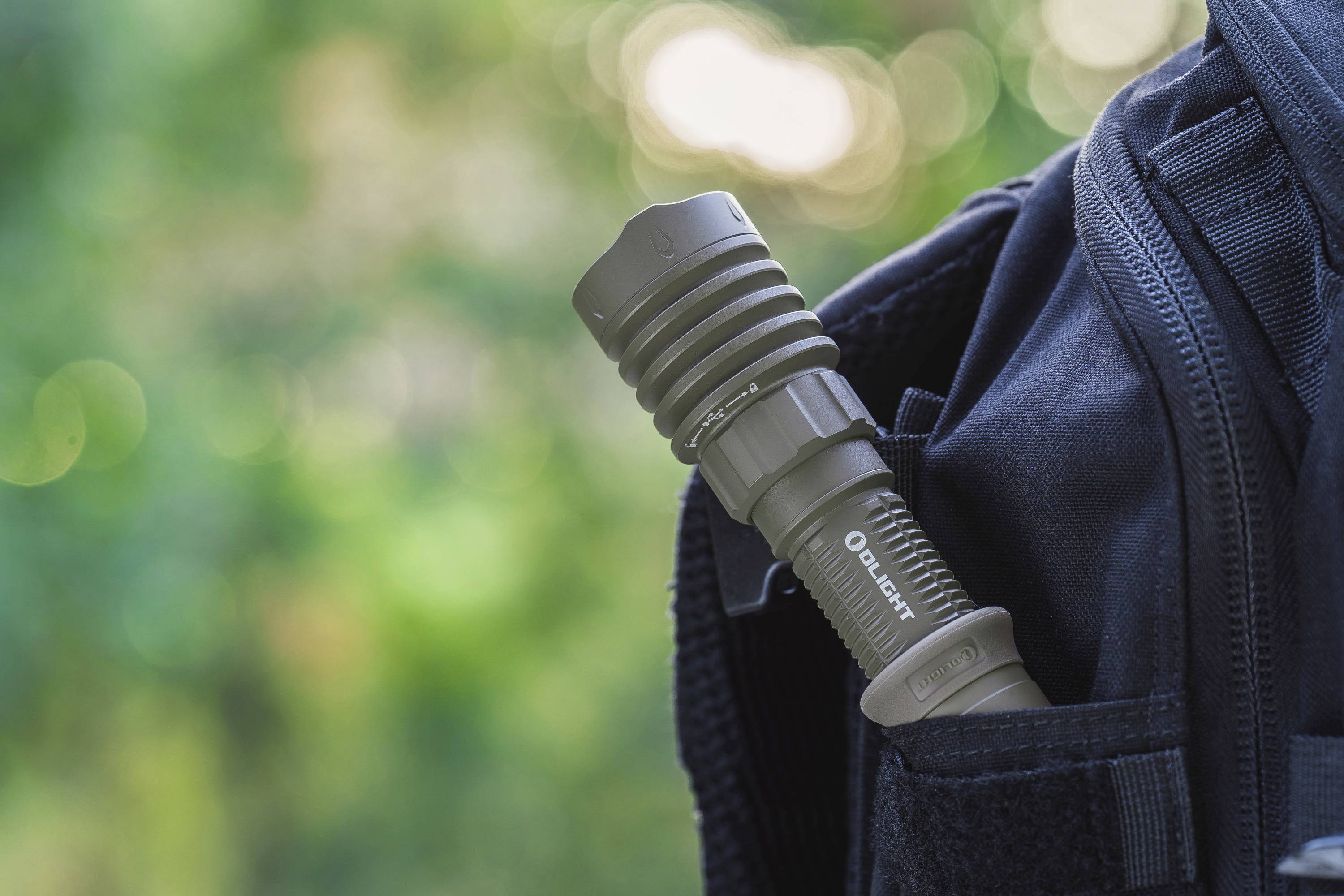 Une lampe de poche est rangée dans la poche latérale d'un sac à dos, devant un arrière-plan flou.