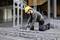 Un ouvrier en tenue de protection est agenouillé et fixe des renforts métalliques à l'aide d'un outil électrique sur un chantier de construction.
