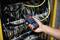 Une main tient un appareil de mesure numérique et mesure le courant dans un armoire électrique contenant plusieurs câbles et connexions.