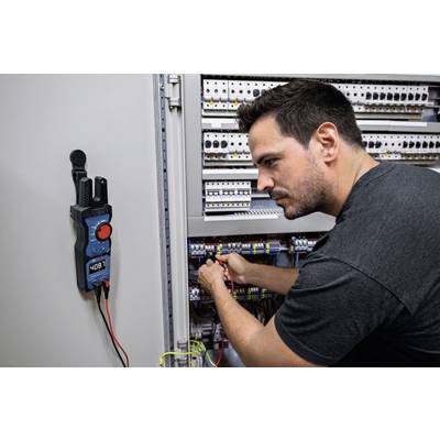 Un homme travaille de manière concentrée sur un armoire électrique, un appareil de mesure numérique fixé à côté.