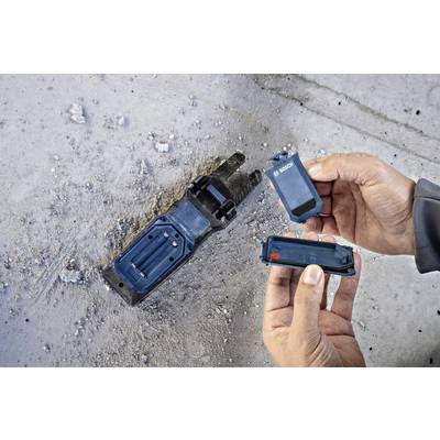 Deux mains tiennent un embout de vissage Bosch et une batterie. Un autre outil Bosch est posé sur un sol de type béton.