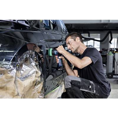 Un homme polit une voiture à l'aide d'une machine dans un atelier. Il porte des lunettes de protection et des vêtements noirs. La voiture est partiellement recouverte.