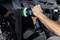 Une image détaillée montre une personne qui polit avec une polisseuse le vernis brillant d'une voiture noire jusqu'à obtenir un fini miroir.