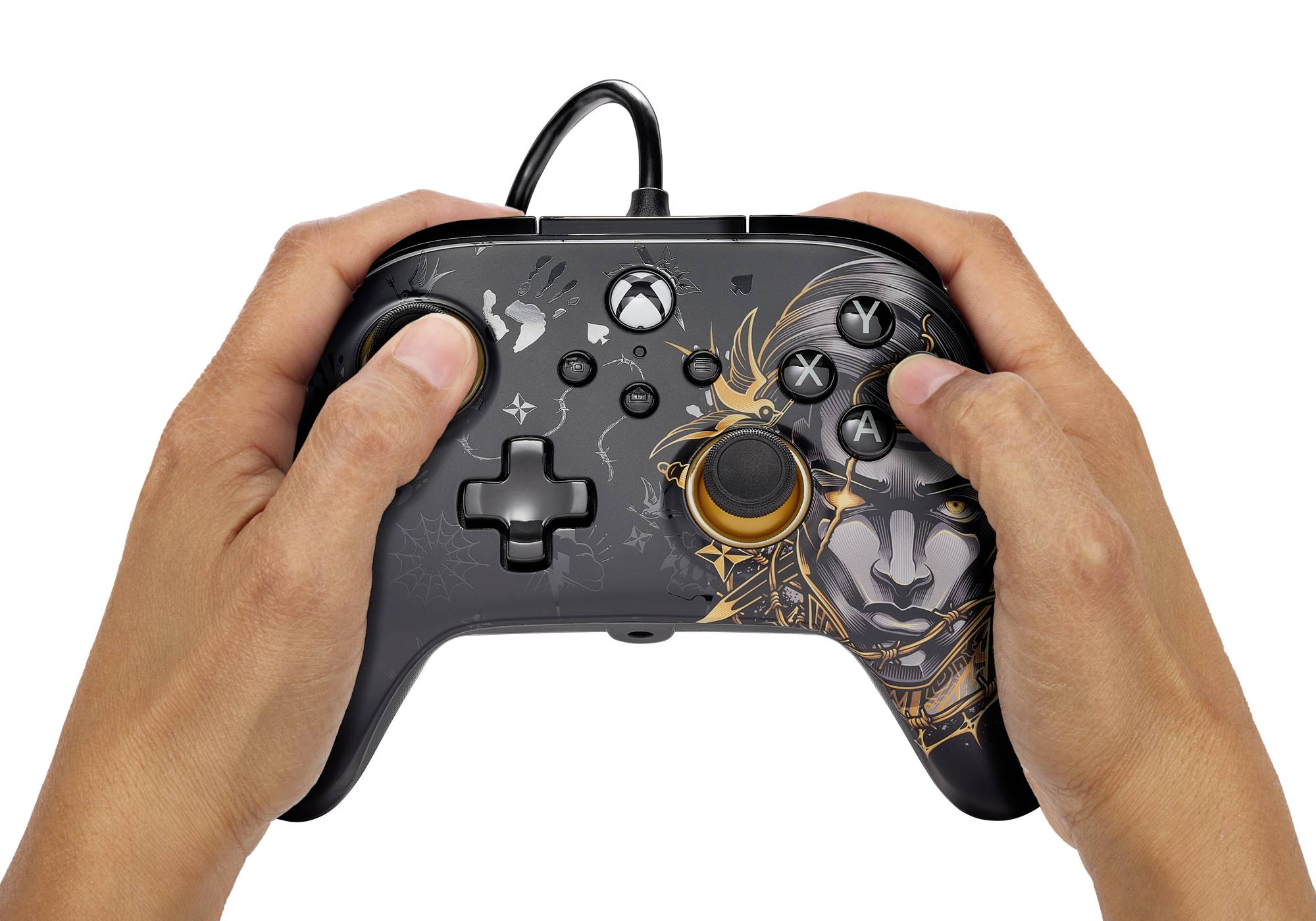 Des mains tiennent une manette de jeu vidéo noire au design artistique et avec un câble, prête à jouer.