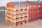 Bâtiment en brique avec des fenêtres peintes en bleu. Au premier plan, un échafaudage en bois est installé, s'étendant sur plusieurs étages.