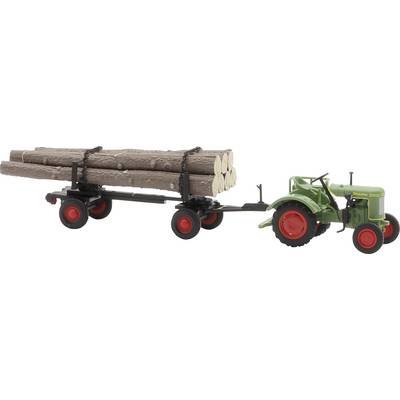 Un tracteur vert tire une remorque chargée de grumes. La remorque a quatre roues rouges, et les bûches sont arrimées par des chaînes.