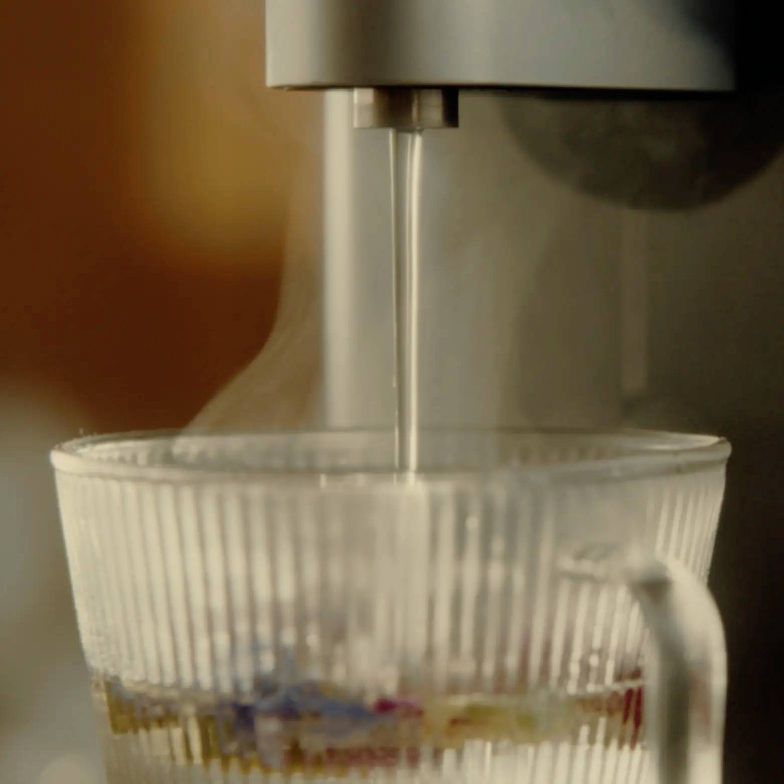 L'eau coule d'un distributeur dans une cruche. La cruche est presque vide, avec seulement un peu d'eau au fond.