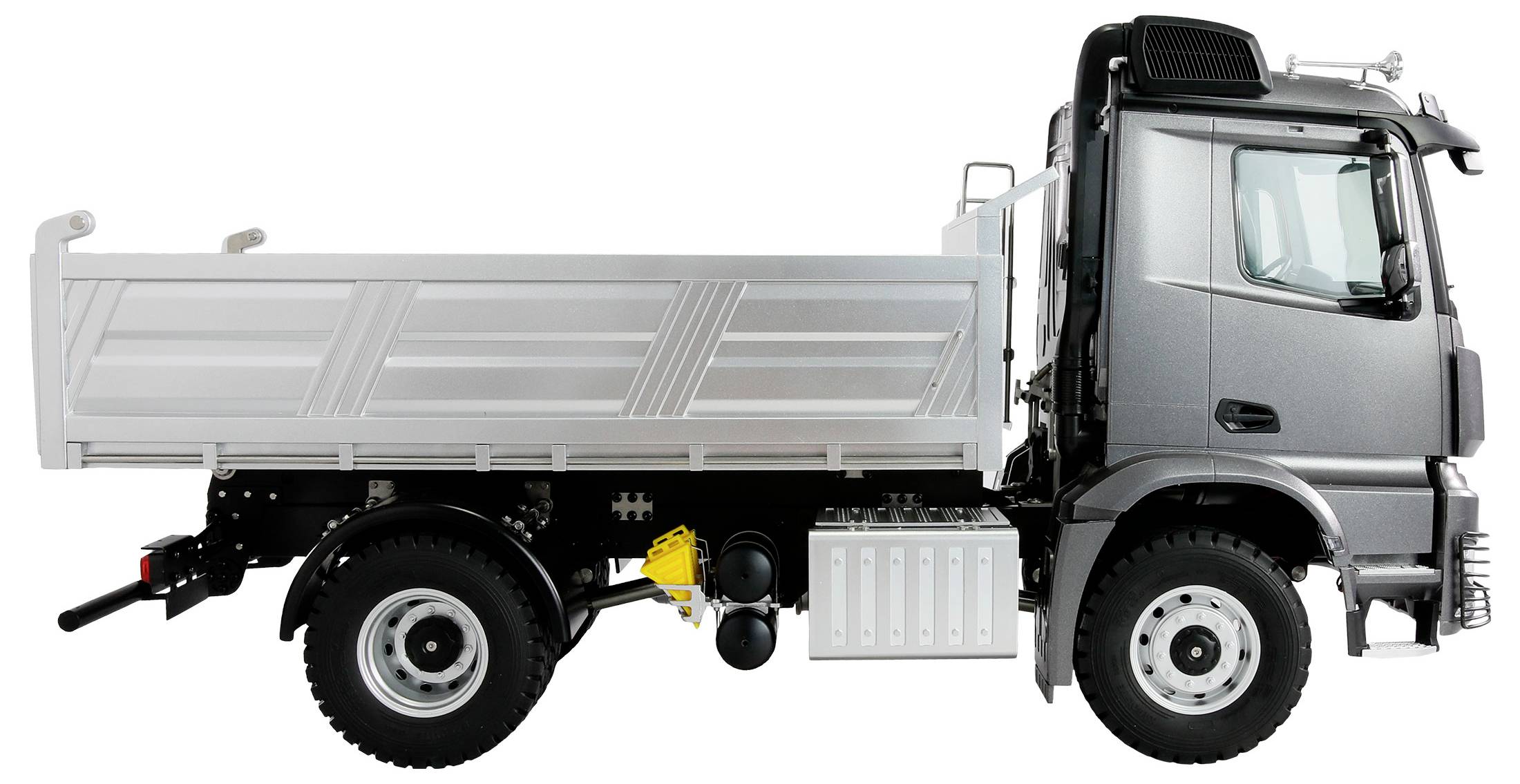 Vue latérale d'un camion gris à benne basculante, adapté au transport de matériaux de construction.