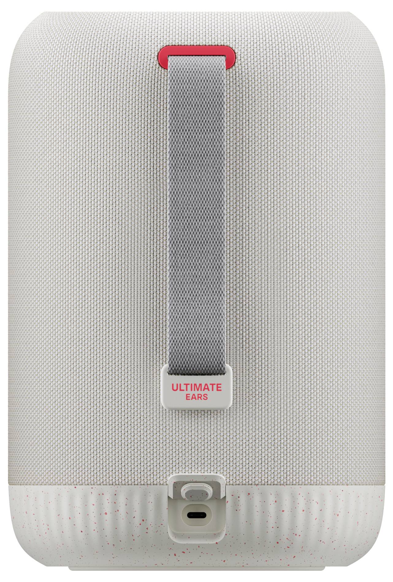 Vue arrière d'un haut-parleur portable blanc avec un accent rouge. Positionné verticalement, il dispose d'une poignée de transport et d'un port de charge sur la partie inférieure.