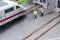 Un train miniature est arrêté devant une gare. Deux personnages en tenue de travail, l'un en jaune, l'autre en rouge, sont sur les voies et gesticulent.