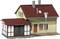 Une maquette de maison avec un toit rouge et une façade jaune-brune, des bâtiments annexes avec un revêtement en bois, et un lampadaire devant.