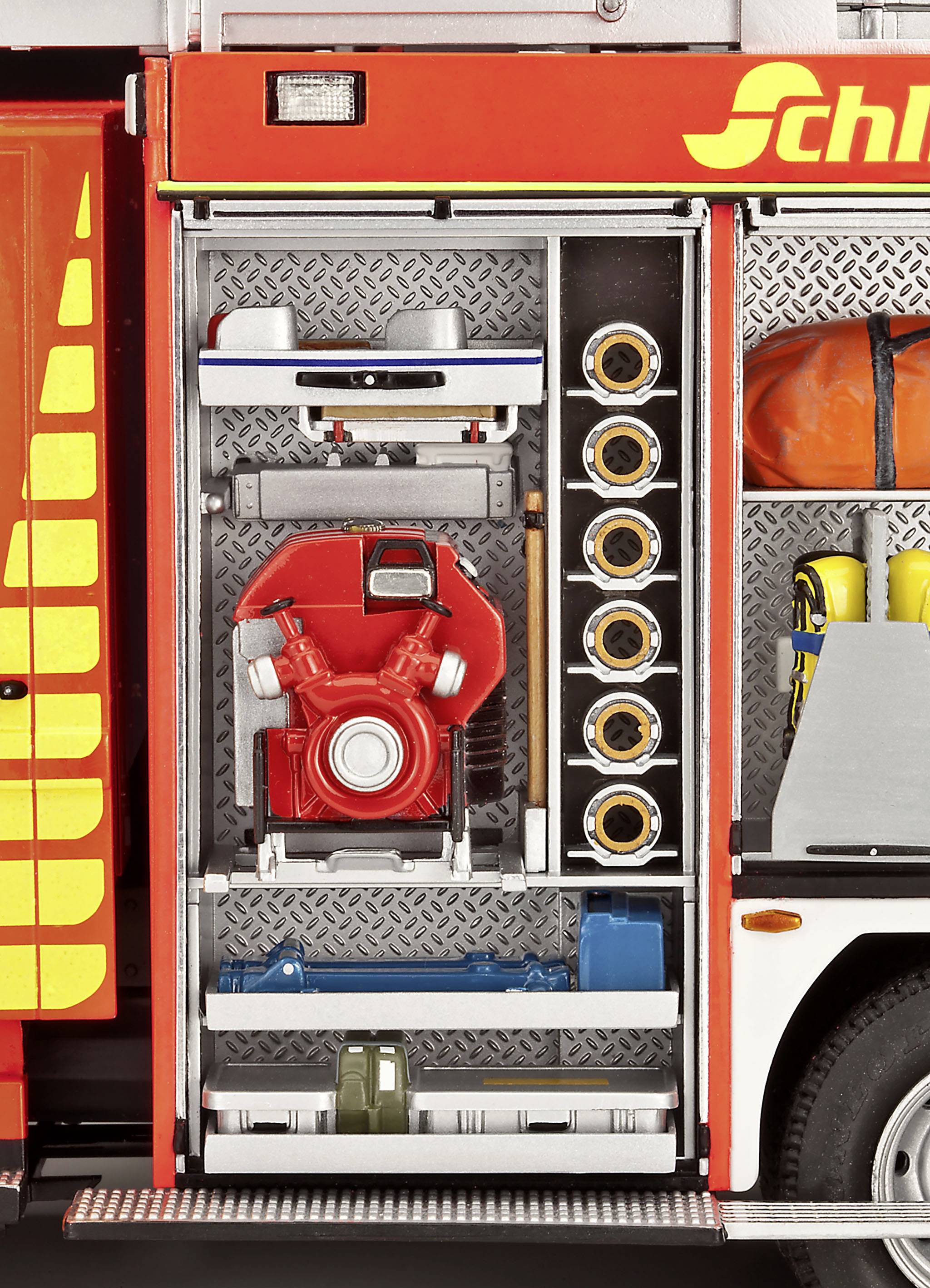 Une voiture de pompiers avec la chambre d'équipement ouverte montre des tuyaux, une pompe et des outils, prêts pour l'intervention.