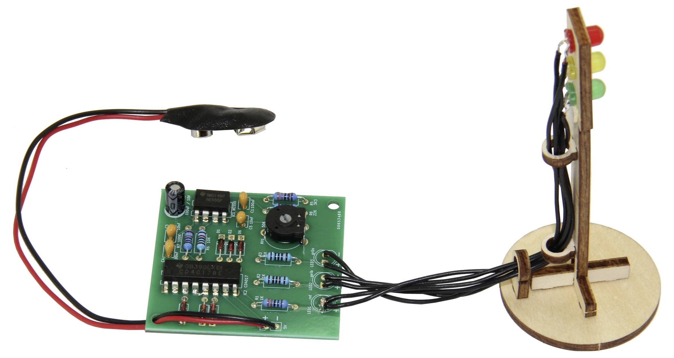 Un circuit électronique relié par des câbles relie une carte de circuit imprimé à un mini feu tricolore contenant des voyants LED rouges, jaunes et verts.