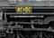Locomotive à vapeur noir et blanc avec un degré élevé de détails, logo jaune AC/DC sur le côté, soulignant l'esthétique industrielle.