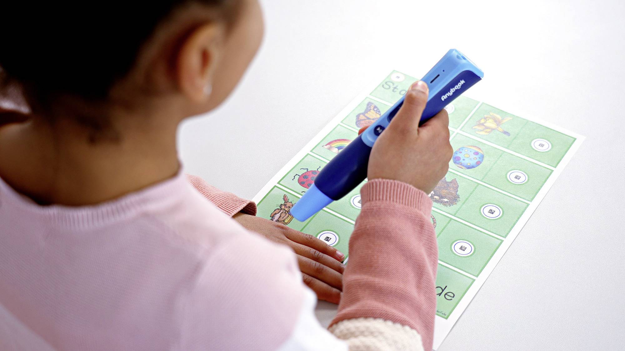 Un enfant utilise un stylo bleu pour résoudre un exercice sur une feuille de travail comportant des images d'animaux et des symboles.