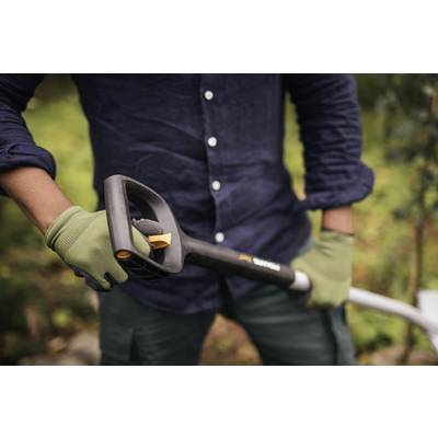 Une personne portant une chemise bleu marine et des gants verts tient une pelle de jardin. Un arrière-plan vert flou est visible.