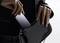 Une personne glisse un smartphone dans un sac à main noir, mettant en valeur le design élégant et la portabilité de l'appareil.