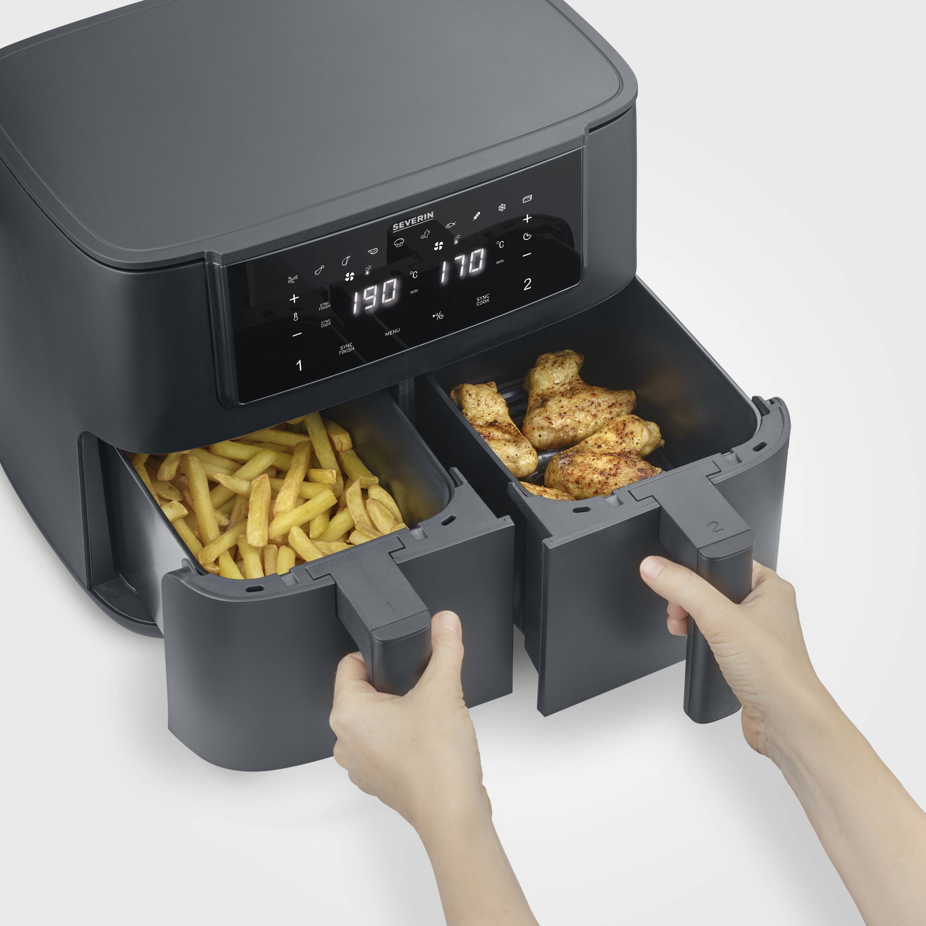 Une friteuse à air chaud avec deux tiroirs : à gauche se trouvent des frites, à droite sont disposées des ailes de poulet. Une main tire les tiroirs.