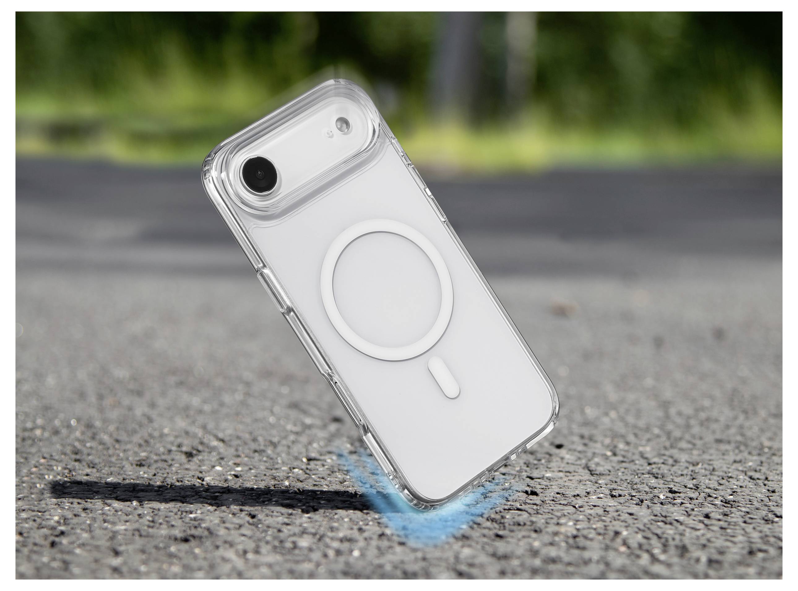 Un téléphone dans un étui transparent est montré en plein air au-dessus du bitume, avec des lignes de mouvement indiquant sa chute.